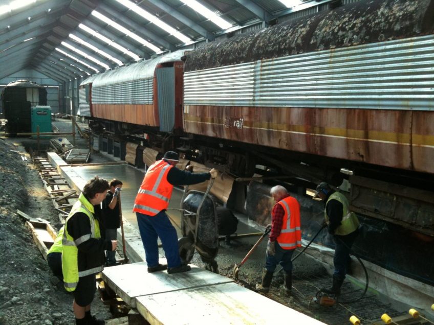 Trust volunteers place concrete to form central floor slabs in the inspection pits